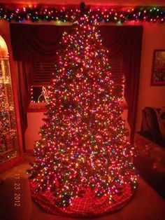 a large christmas tree is lit up with multicolored lights in the living room