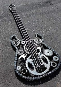 an upside down guitar sitting on the ground with gears attached to it's neck