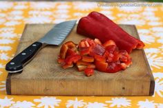 sliced up red peppers on a cutting board with a large knife next to the chopping block