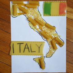 a piece of paper with the word italy cut out of it and some pasta on top