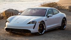 a white sports car parked in front of the ocean