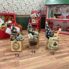 three miniature christmas trees in small boxes on the floor next to other ornaments and decorations