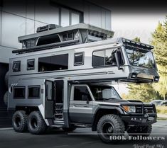 an off road vehicle parked in front of a tall building with windows on the roof