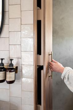 a woman opening the door to a bathroom with soap and lotion bottles on it