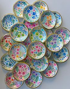 a pile of colorful plates sitting on top of each other in front of a white wall