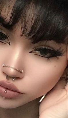 a close up of a person with piercings on her nose and nose ring in front of their face