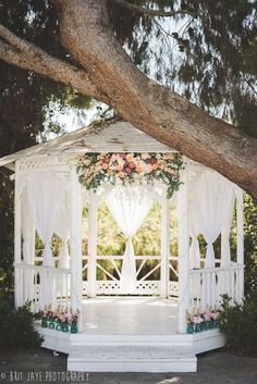 a white gazebo with curtains and flowers on it