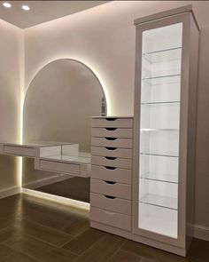 an empty dressing room with white furniture and lights on the wall, along with a large mirror