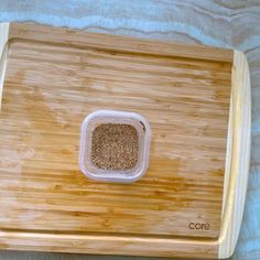 a wooden cutting board with a small bowl on top of it and some spices in the bottom