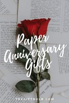 a red rose sitting on top of an open book with the words paper anniversary gifts