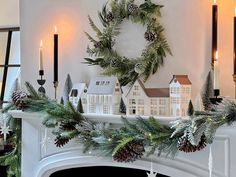 a mantel decorated for christmas with pine cones and greenery