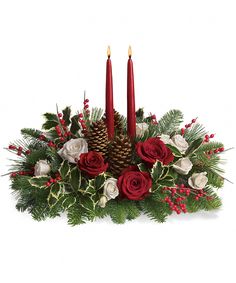 a christmas centerpiece with two candles and evergreens in the center, surrounded by red roses