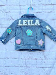 Our custom denim jackets for kids have the name of your choice sewn on the upper back panel of the jacket in chenille letter patches. These personalized jean jackets have additional chenille patches that are sewn on the back, sleeves and front. These name jackets for girls make the perfect customized gift for babies, toddlers and girls! DETAILS: -preppy style chenille patches with gold outline -customize to spell your child's name in 5 color options (pink, purple, white, turquoise, rainbow) -GAP Customizable Blue Denim Jacket, Customizable Cute Denim Jacket, Customizable Denim Jacket For Fall, Customizable Blue Denim Jacket For Spring, Customizable Cute Cotton Outerwear, Customizable Blue Denim Jacket With Long Sleeves, Cute Customizable Cotton Outerwear, Customizable Denim Outerwear For Fall, Customizable Cute Fall Outerwear