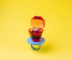 a red and yellow object sitting on top of a blue table next to a yellow background