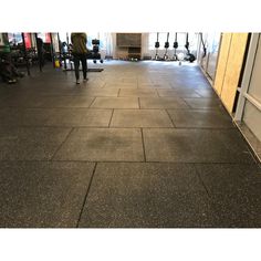 an empty gym floor with people in the background and equipment hanging up on the wall