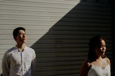 two people standing next to each other in front of a garage door