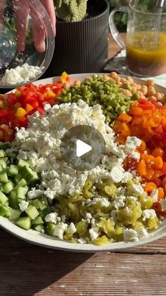 a plate full of different types of vegetables and cheese on a wooden table next to bowls with utensils