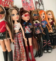 many dolls are lined up against a wall with posters on the wall behind them and one is wearing red boots