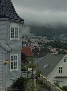 an umbrella is hanging on the side of a house in front of some houses and mountains