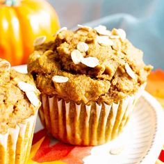 two muffins sitting on top of a plate with pumpkins in the background