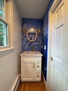 a white sink sitting under a mirror in a bathroom next to a door and window