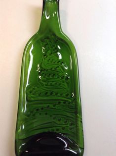 a green glass bottle sitting on top of a white wall