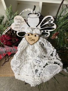 a white angel ornament with a wooden heart on it's back and words written in the middle