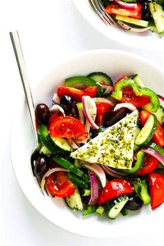 two bowls filled with different types of vegetables next to each other on a white surface