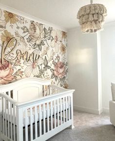 a white crib in front of a floral wallpaper