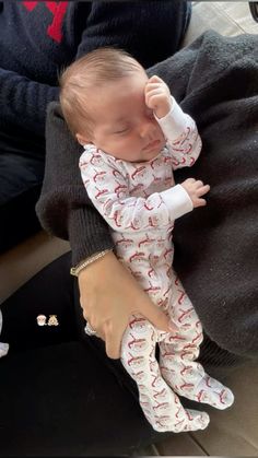 a woman holding a baby in her arms while she sleeps on top of someone's lap