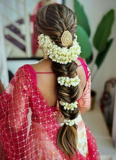 a woman with long hair and flowers in her hair, wearing a red sari