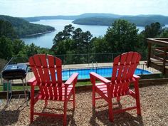 two red chairs sitting on top of a patio next to a swimming pool