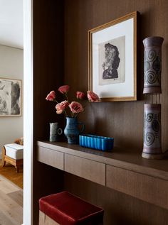 vases and flowers sit on a shelf in the entryway