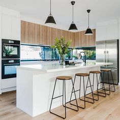 a kitchen with an island and bar stools next to the counter top in front of it