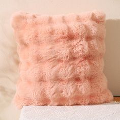 a pink pillow sitting on top of a white bed