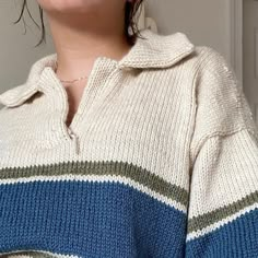 a woman with her eyes closed standing in front of a door wearing a striped sweater