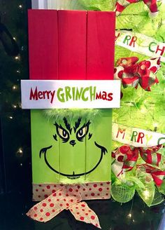 a green bag with the grinch face on it is next to a christmas tree