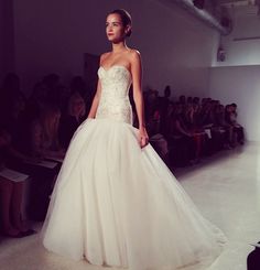 a woman in a wedding dress walking down the runway