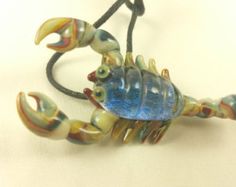 a blue and yellow glass crab sitting on top of a white table next to a black cord