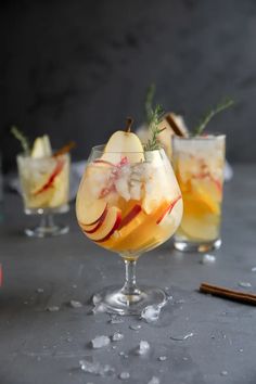 two glasses filled with apple cider cocktails and cinnamon sticks next to them on a table