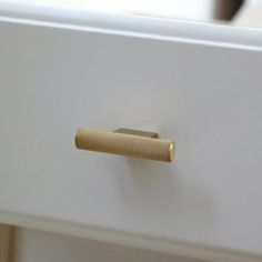 a white drawer with a gold handle on it