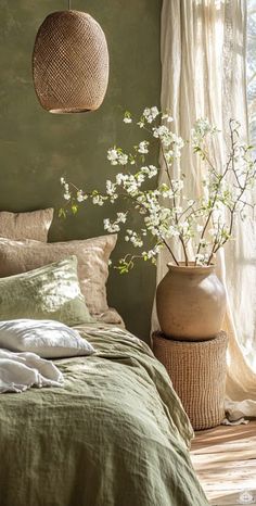 a bedroom with green walls and white flowers in a vase next to the bed,