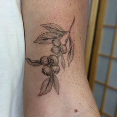 an olive branch tattoo on the right side of the leg, with leaves and berries