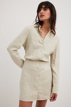 This mini dress is made of linen and features a shirt collar. It has a button closure and an elasticized waist. The mini dress has long sleeves with double button cuffs. Elegant Long Sleeve Neutral Mini Dress, Casual Beige Linen Long Sleeve Dress, Casual Beige Long Sleeve Linen Dress, Beige Long Sleeve Casual Linen Dress, Beige Collared Shirt Dress With Button Cuffs, Beige Shirt Dress With Button Cuffs For Spring, Classic Long Sleeve Mini Dress For Daywear, Chic Long Sleeve Linen Dress With Buttons, Elegant Long Sleeve Beige Linen Dress