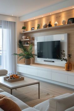 a living room filled with furniture and a flat screen tv mounted on a wall next to a window