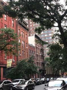 many cars are parked on the street near tall buildings