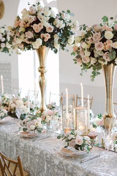 the table is set with candles and flowers in tall vases on top of it