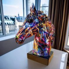 a brightly colored horse head on display in front of a window with cityscape