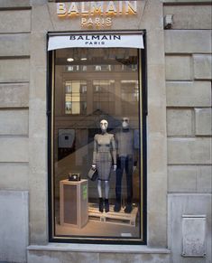 two mannequins in a window display on the side of a building