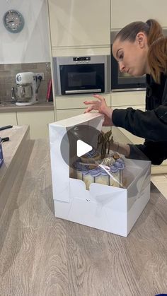 a woman opening up a box on top of a counter